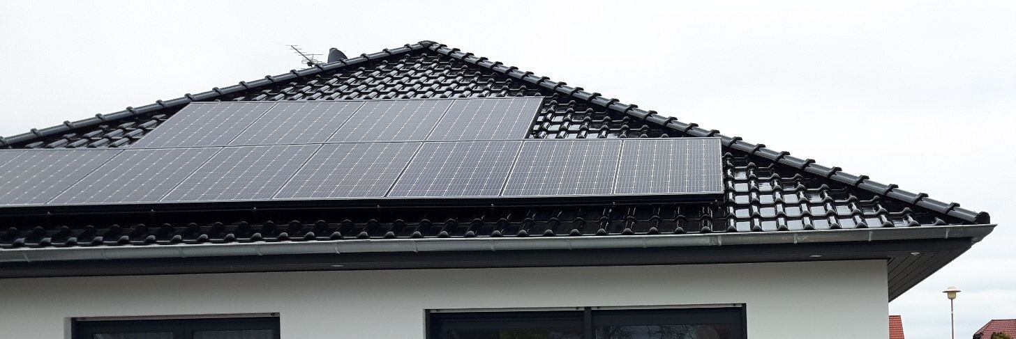 Dach eines Einfamilienhauses mit installierten Solarpanelen auf dunklen Ziegeln.