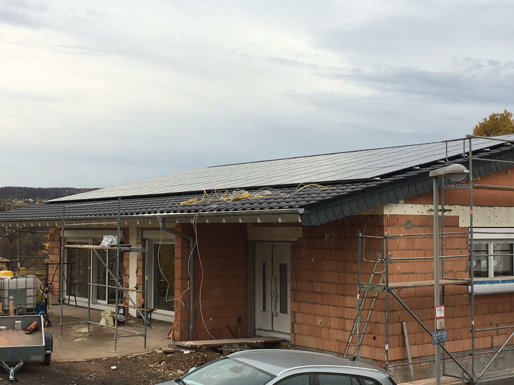 Neubau mit roten Ziegeln, Solarpanele auf dem Dach, Gerüst und Bauwerkzeuge.