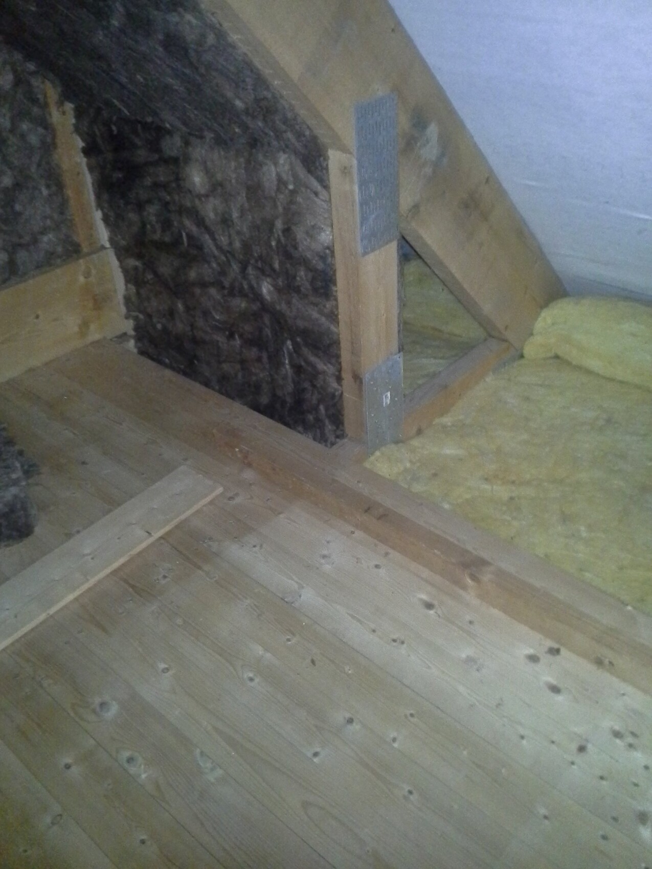 Dachboden mit Holzboden, gelber Dämmstoff und Holzkonstruktion