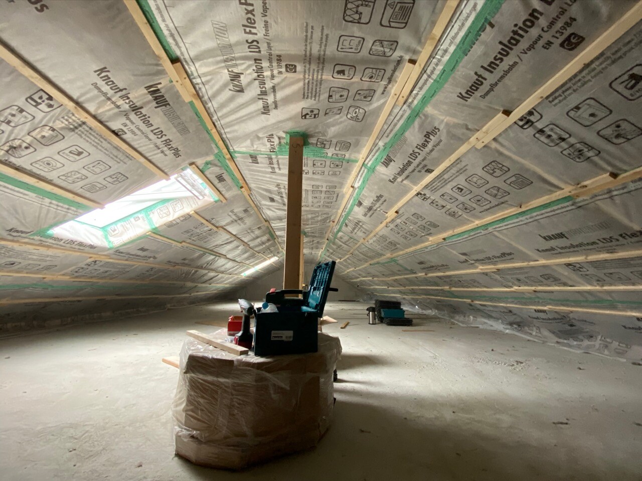Dachboden mit Dämmung an Sparren, Lichtfenster und Werkzeugkasten.