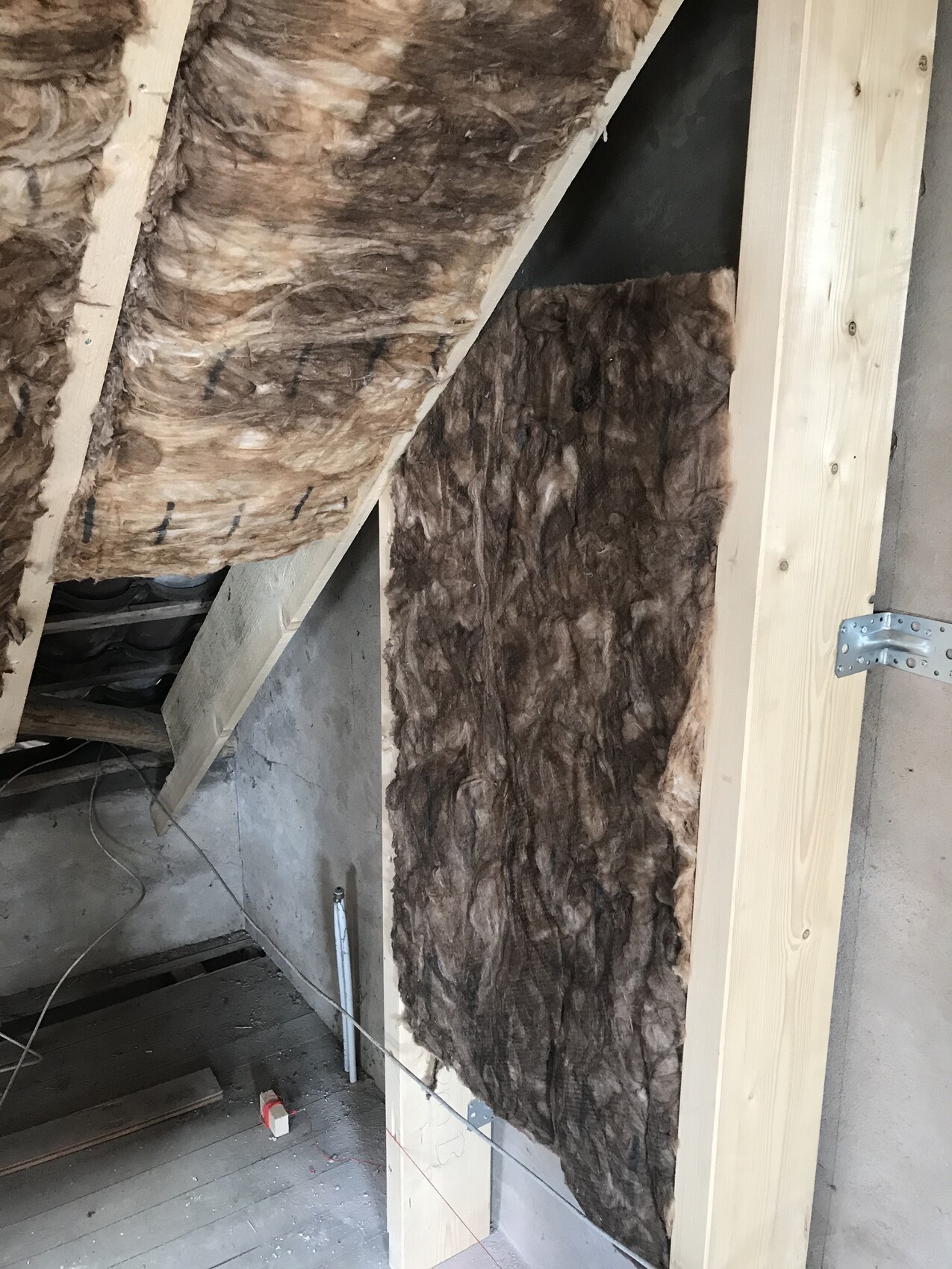 Dachboden-Wand mit brauner Mineralwolle-Dämmung zwischen Holzrahmen.