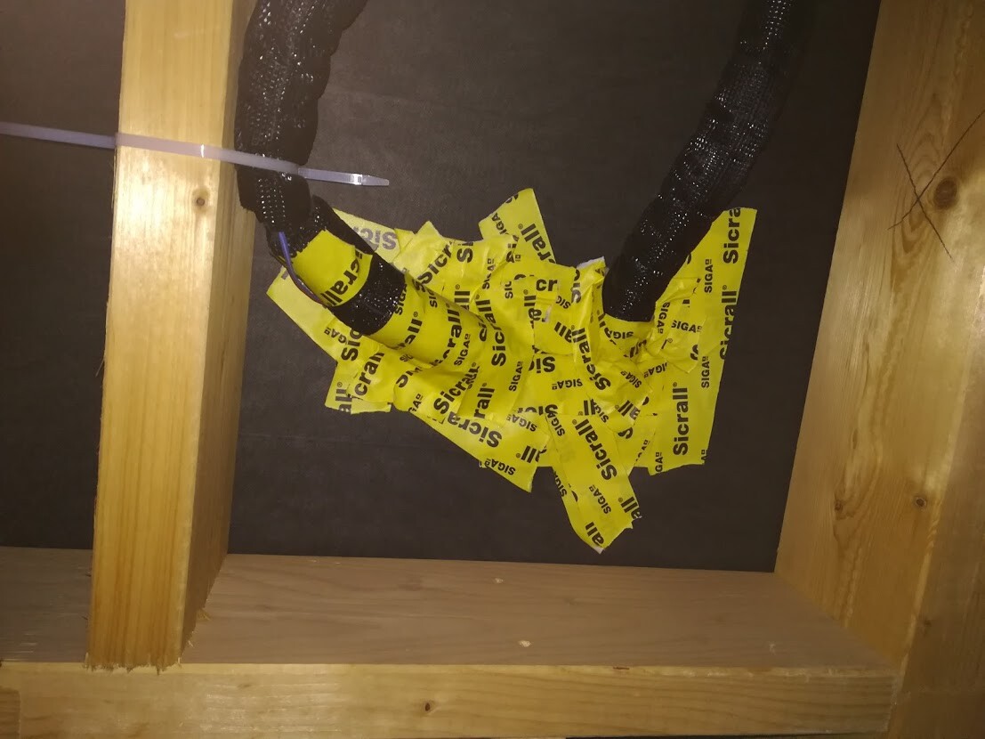 Herzförmige Anordnung aus gelbem Warnband vor schwarzem Hintergrund, von Holzbalken eingerahmt.
