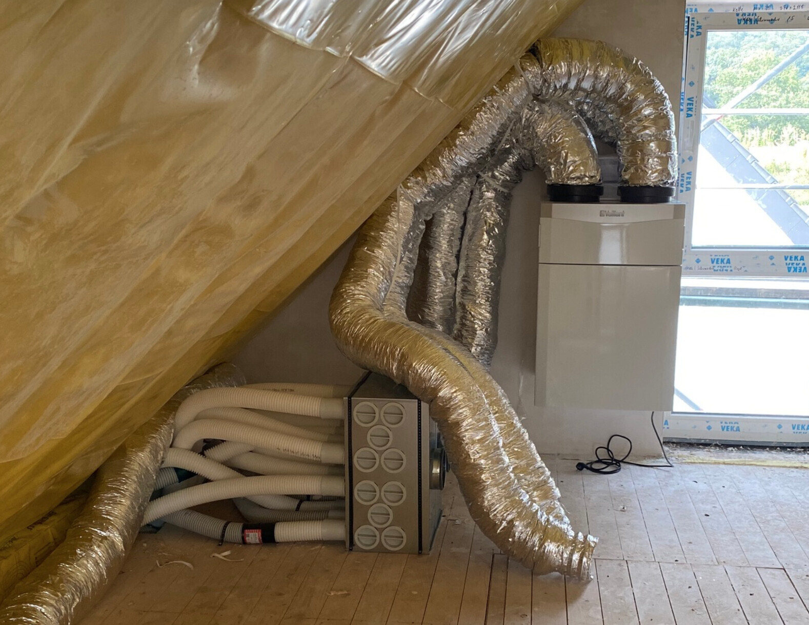 Dachboden mit Vaillant Heizgerät und silbernen flexiblen Alu-Lüftungsrohren.
