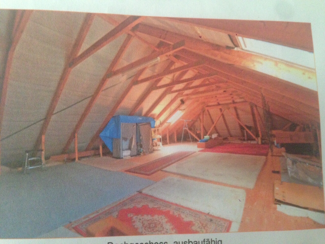 Dachboden mit sichtbaren Holzbalken, Dachstuhl und Bauutensilien im Raum