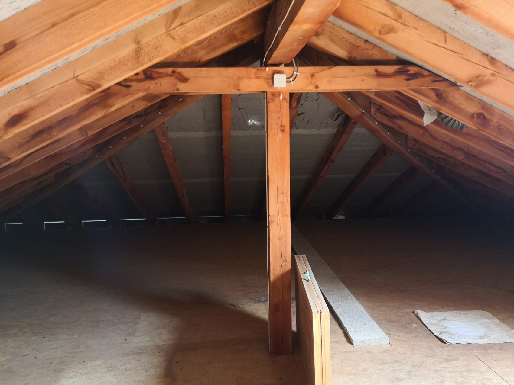 Dachboden mit sichtbarem Dachstuhl aus Holz, zentrale Balkenstütze und leerem Raum.