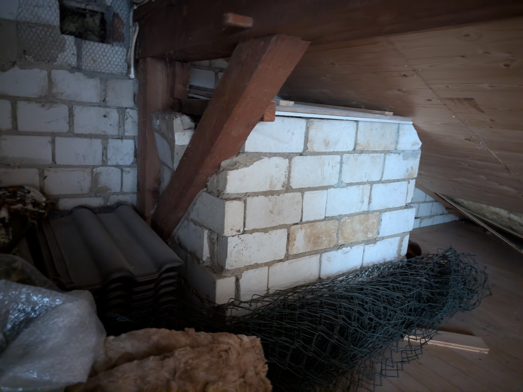 Dachboden mit rohem Mauerwerk, Holzbalken und Drahtgitter im Rohbau