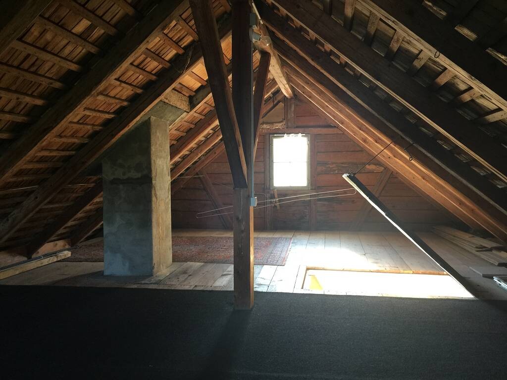 Dachboden im Rohbau mit Holzbalken, Dachstuhl und Fenster, Holzfußboden