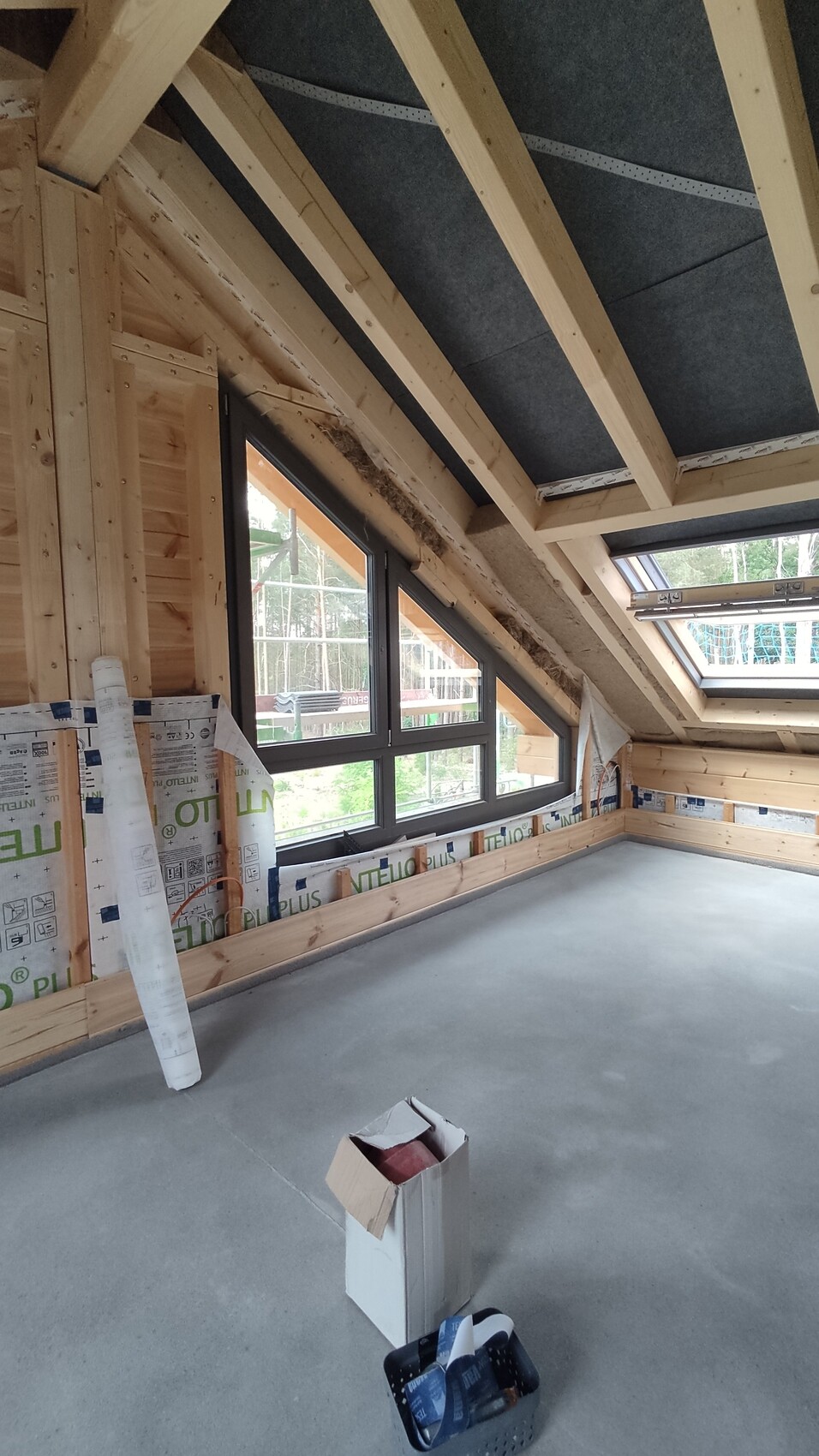 Dachgeschoss-Bau: sichtbare Holzbalken, große Dachfenster, unfertiger Innenausbau.