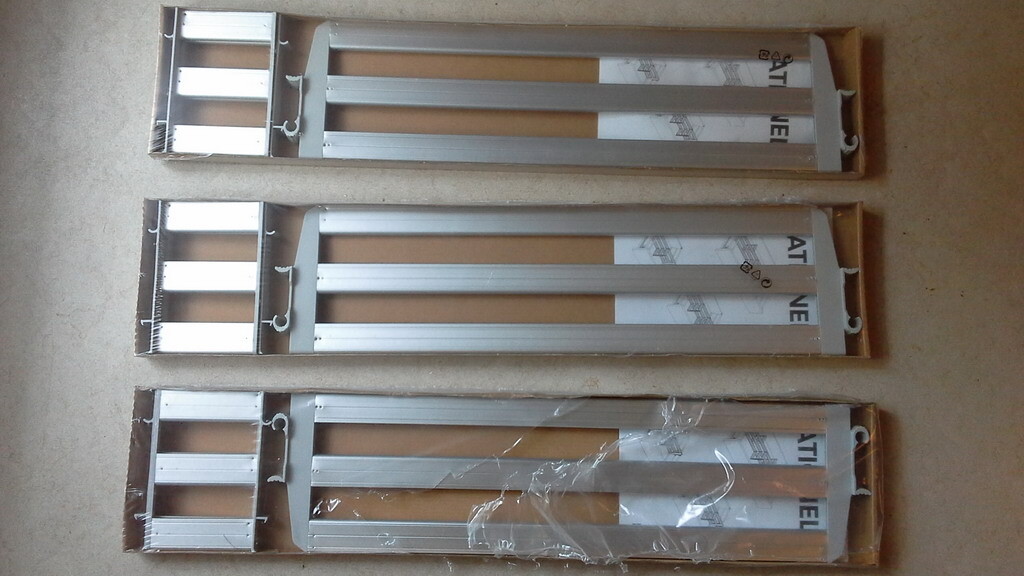 Drei lange Aluminium-Treppenteile liegen auf dem Boden, montagebereit
