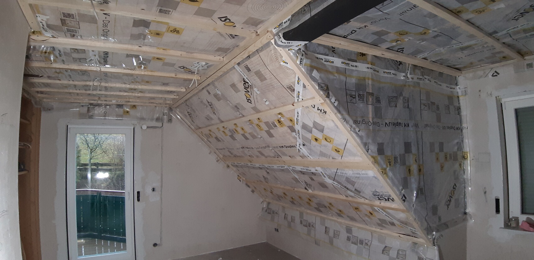 Dachboden-/Dachraum mit Holzbalken, Dämmfolie und Renovierungsarbeiten im Innenraum.
