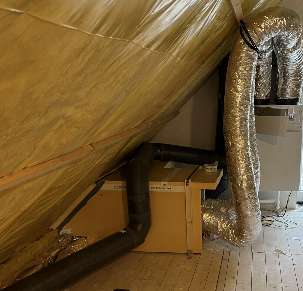 Dachboden mit Dämmung, flexiblen Luftkanälen und Haustechnikinstallation.