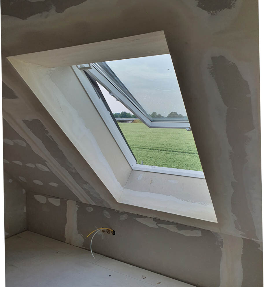 Helles Dachfenster mit Blick aufs grüne Feld; unfertige Innenwand mit Spachtelarbeiten und Kabeln.