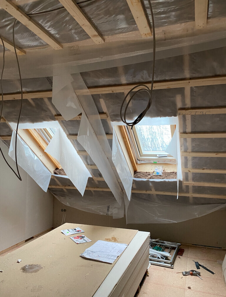 Dachboden-Bauarbeiten: Dachfenster, Folie, Holzrahmen, Werkzeuge, Baupläne.