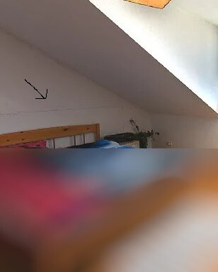 Schlafzimmer im Dachgeschoss mit schräger Decke und Holzbett