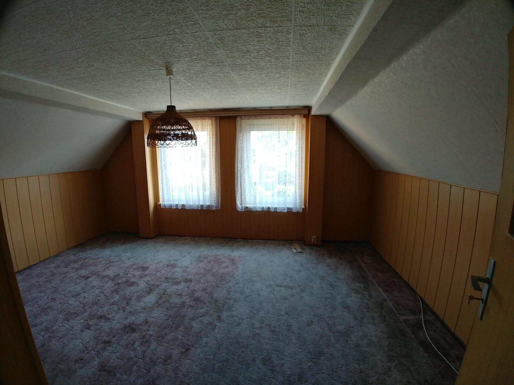 Dachgeschoss-Wohnzimmer mit Holzverkleidung, Spitzenvorhänge und Hängeleuchte