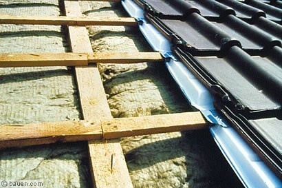 Dachkonstruktion mit Holzbalken und Dachziegeln im Bauprozess