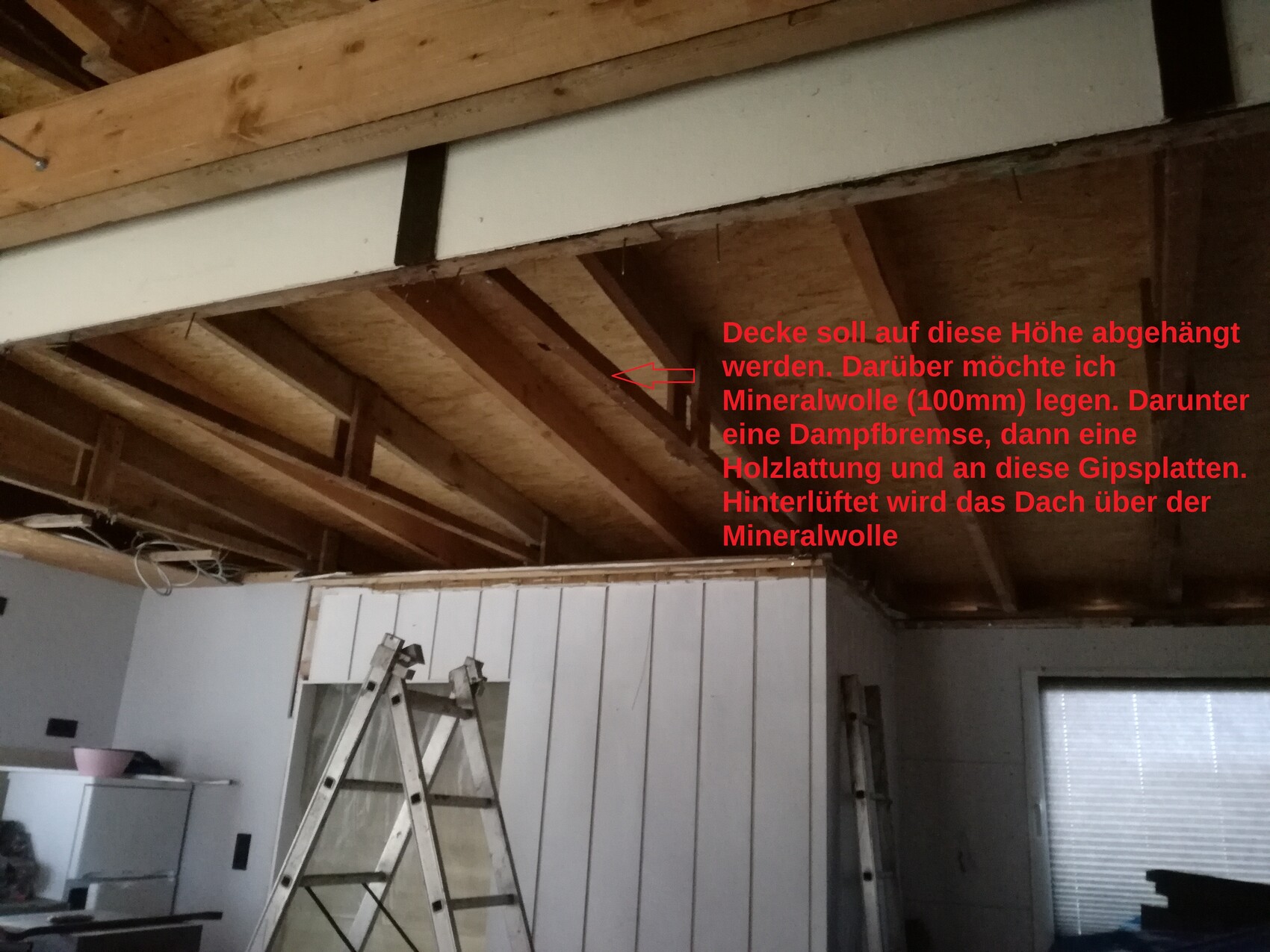 Baustelle mit sichtbaren Dachbalken, Holzlatten und Leiter im Rohbau