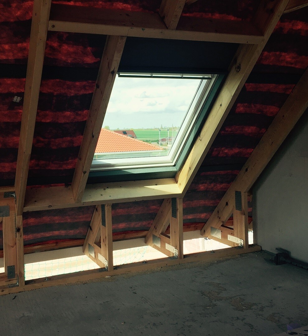 Dachgeschoss-Rohbau mit Holzbalken, Dachfenster und Aussicht auf Dächer