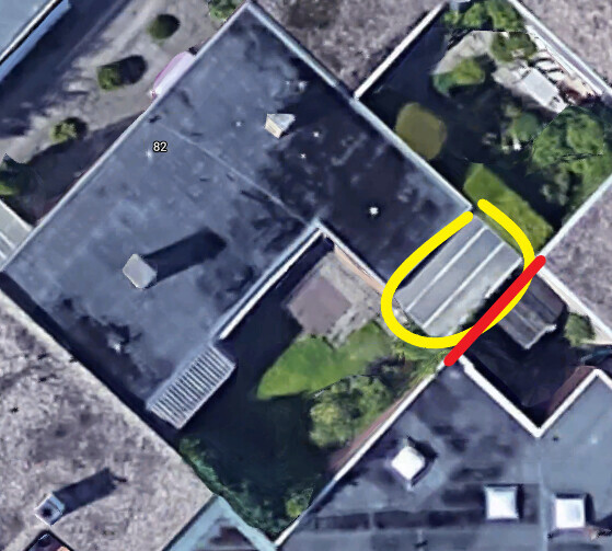 Vogelperspektive auf Flachdächer eines Gebäudekomplexes; gelb markierte Bogenform um eine Dachstruktur.