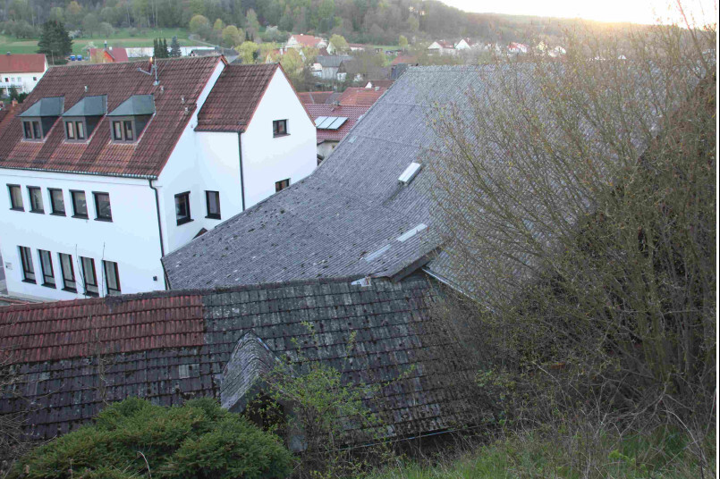 Verschiedene Dachlandschaften eines Wohnviertels auf Hügeln mit Bäumen und weißen Gebäuden