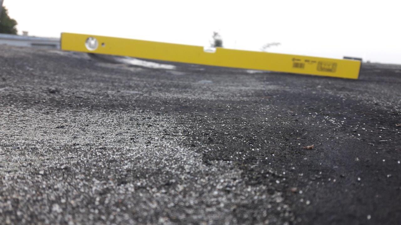 Dachoberfläche mit gelber Wasserwaage auf Asphalt während Bauarbeiten