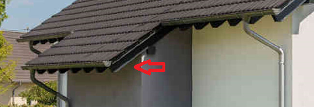 Nahaufnahme der Dachkante eines Hauses; roter Pfeil markiert eine kleine Unebenheit am Rand.