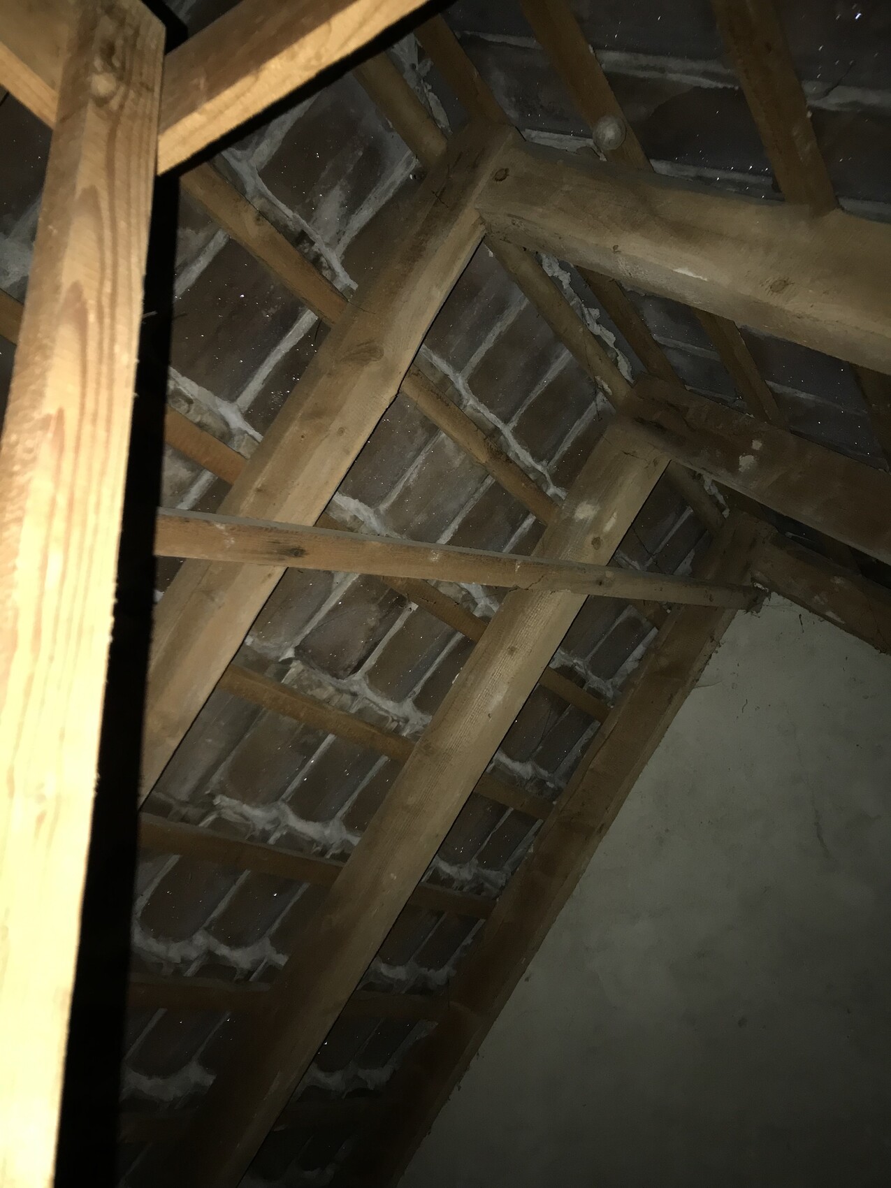 Dachstuhl im Dachboden mit Holzbalken und Ziegeln sichtbar