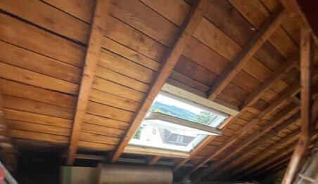 Holz-Dachstuhl mit geöffnetem Dachfenster und Holzbalken im Dachgeschoss