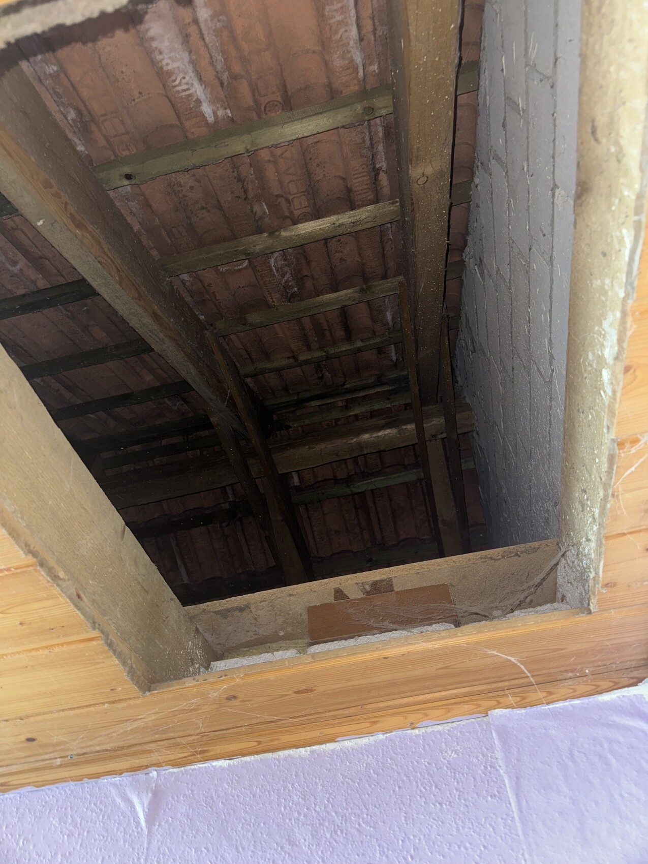 Offene Dachbodenansicht mit sichtbaren Dachstühlen, Holzbalken und Ziegeldecke.