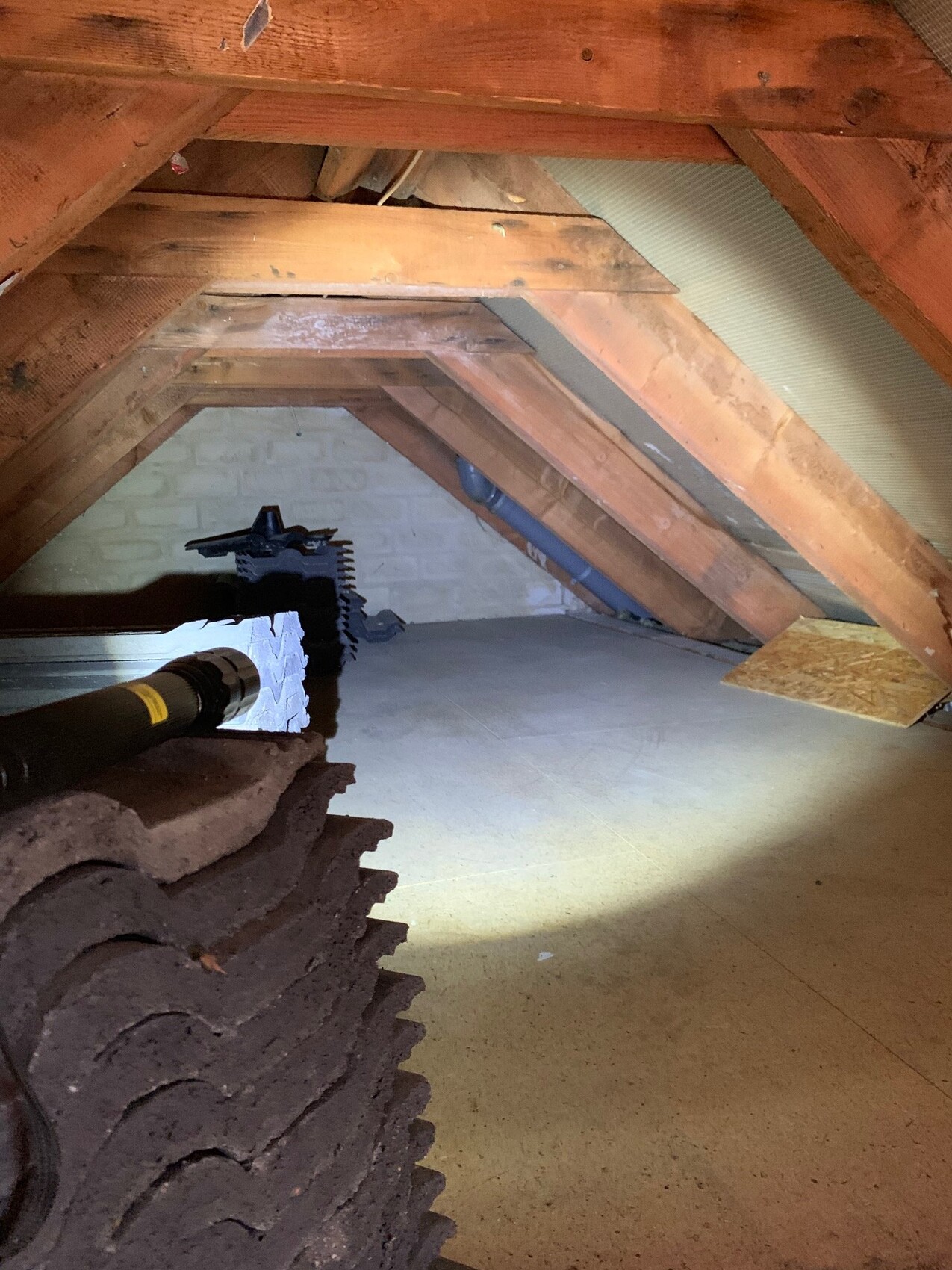 Dachboden mit sichtbarem Holzdachstuhl aus Balken, Dämmung und Baumaterialien.
