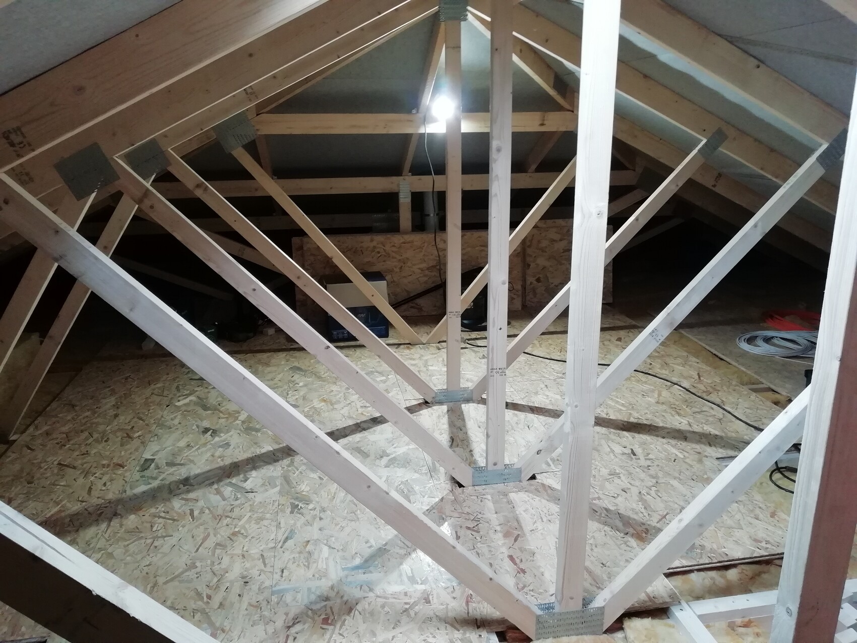 Dachboden mit diagonalem Holzbalkenwerk und OSB-Boden, Baukonstruktion im Dachraum sichtbar.