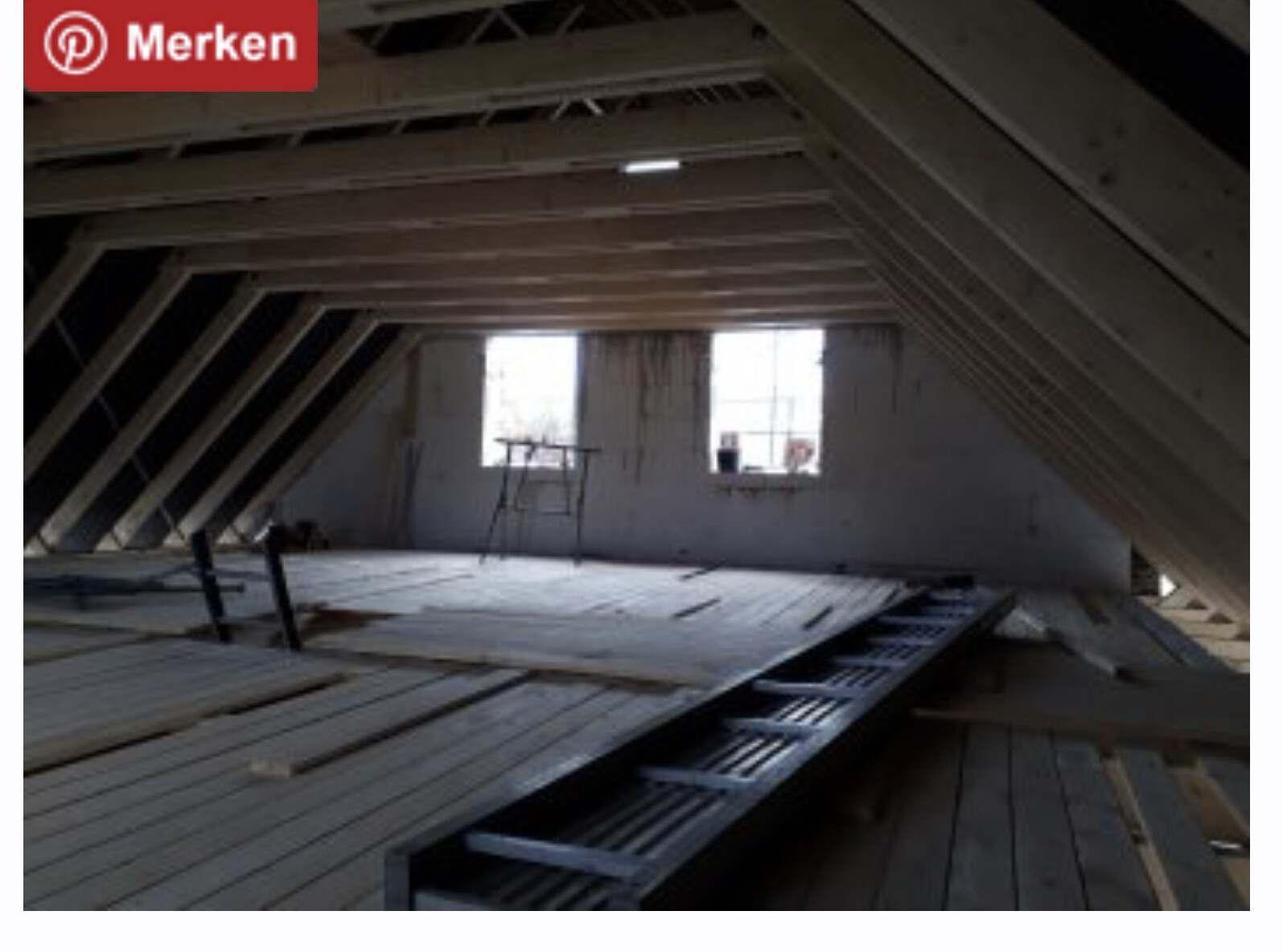 Dachboden im Rohbau mit Holzbalken, Holzböden und zwei Fenstern.