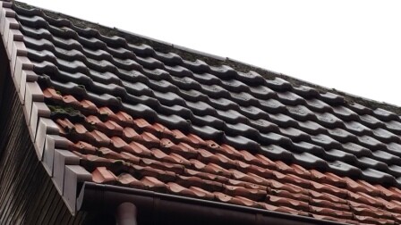 Nahaufnahme von Dachziegeln in Braun und Rot an einer Dachkante