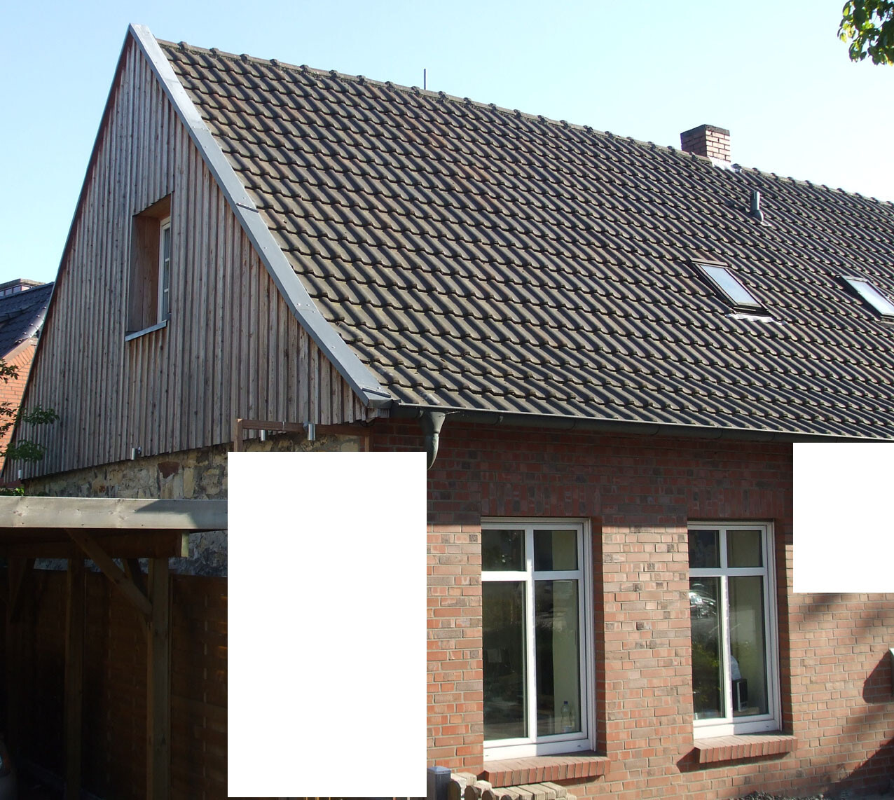 Zweistöckiges Haus mit roter Backsteinfassade, Holzverkleidung am Giebel und Ziegeldach.