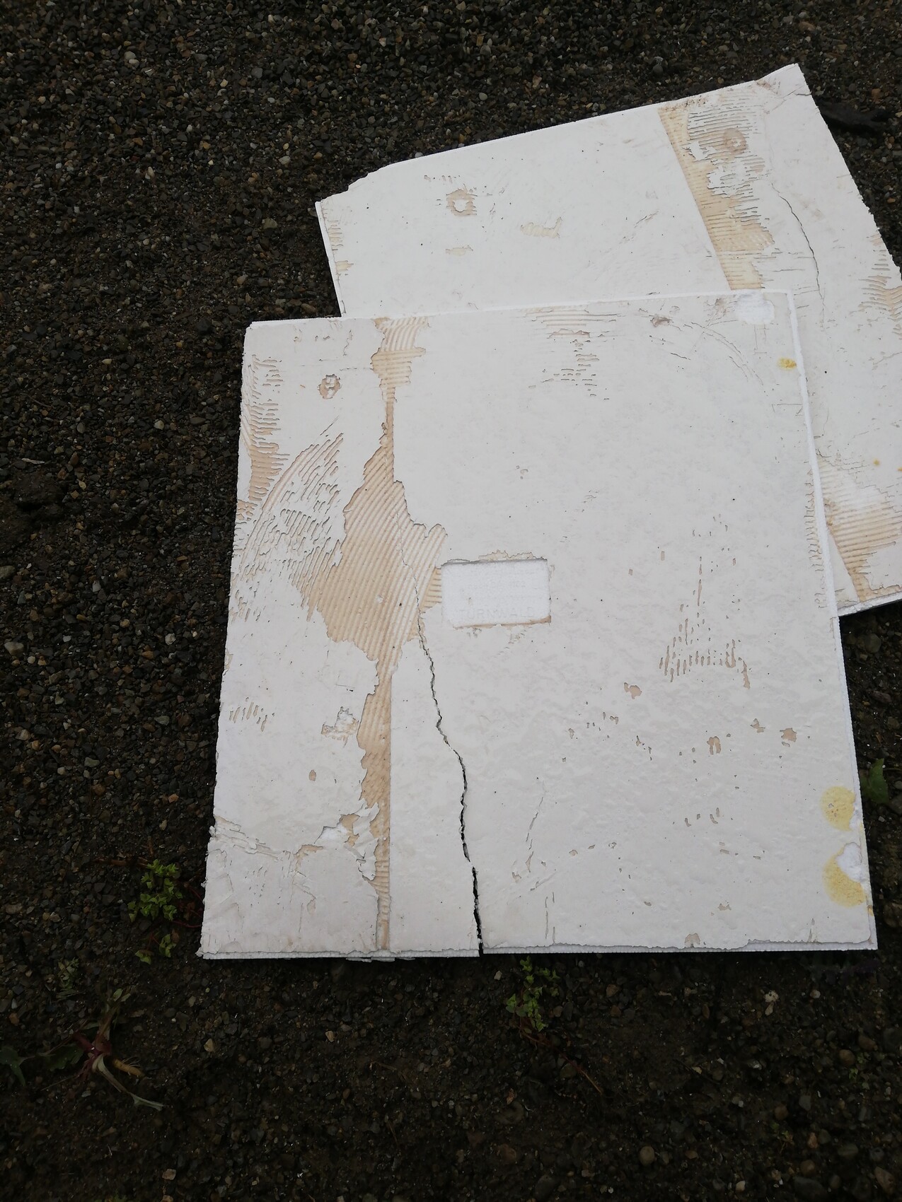 Weiße Styropor-Dämmplatten liegen lose auf dunklem Boden, mit Rissen und Beschädigungen.