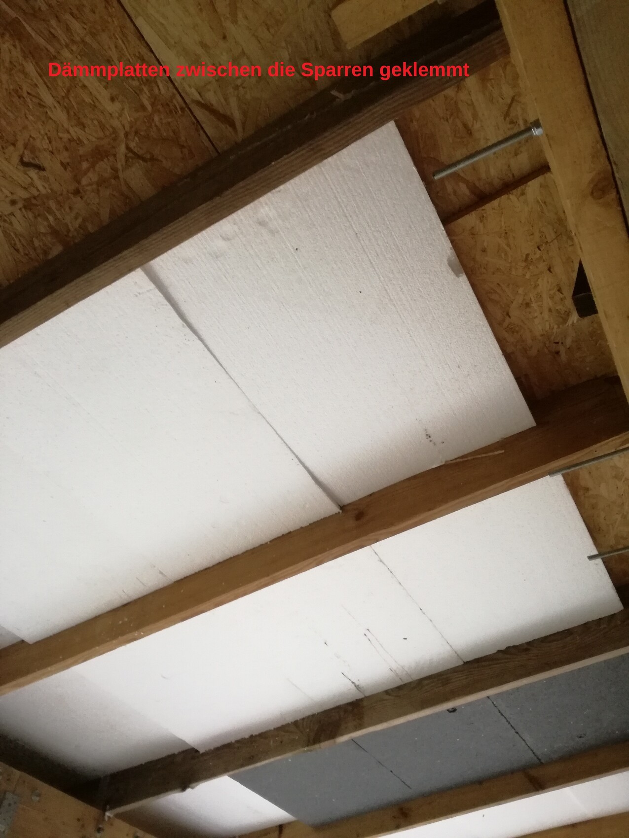 Dämmplatten zwischen Sparren im Dachstuhl während der Bauphase, Holzrahmen sichtbar