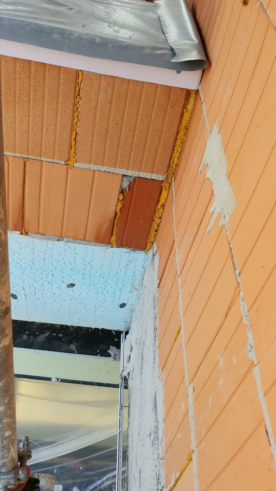 Außenwand aus Ziegeln mit Dämmung und Bauarbeiten auf einer Baustelle.