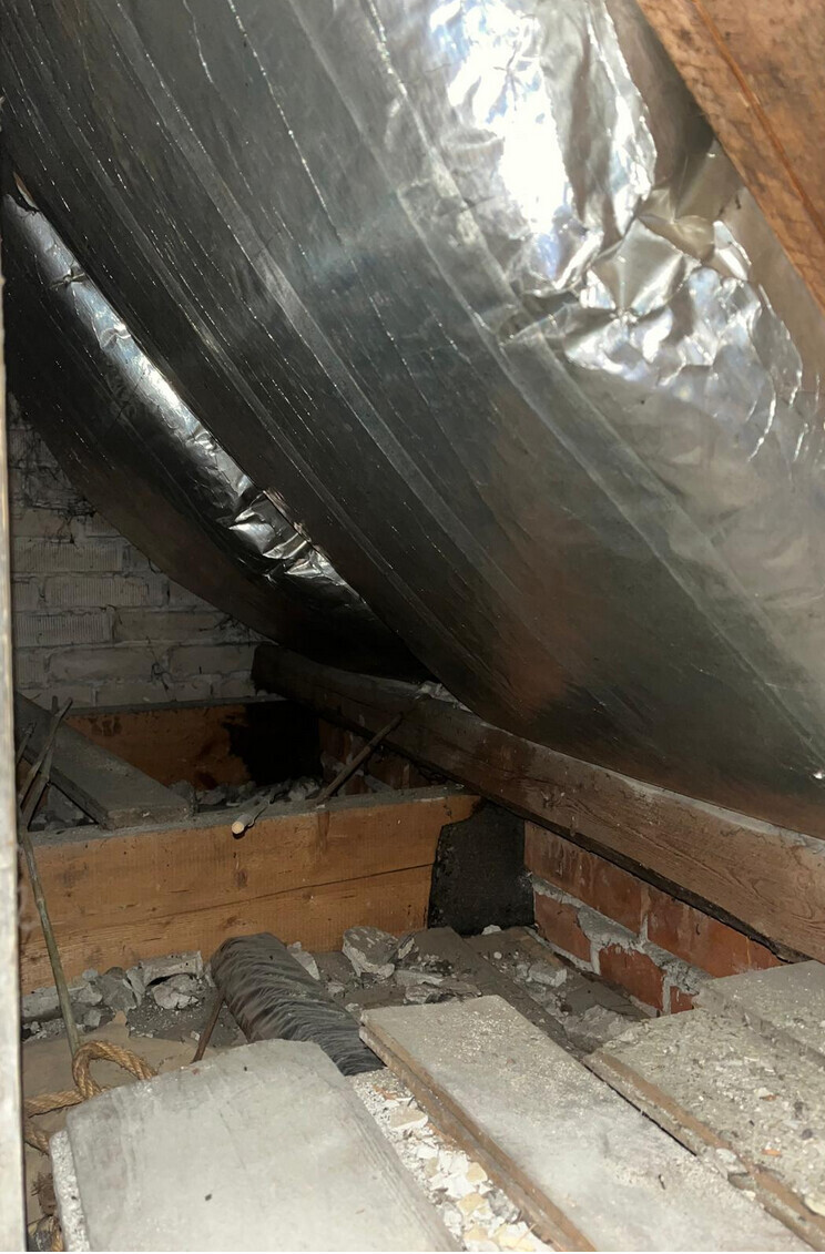 Dachboden mit Aluminiumfolie-Dämmung, Holzbalken und Baumaterialien, unordentlich