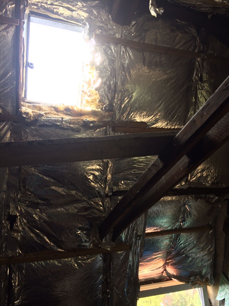 Dachboden mit Holzbalken, reflektierender Dämmfolie und Fensterlicht