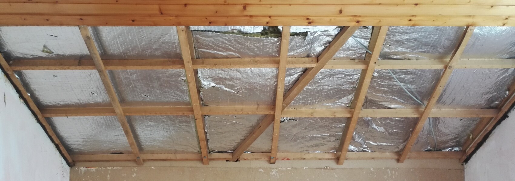 Dachboden mit Holzbalken und reflektierender Dämmfolie zwischen Sparren