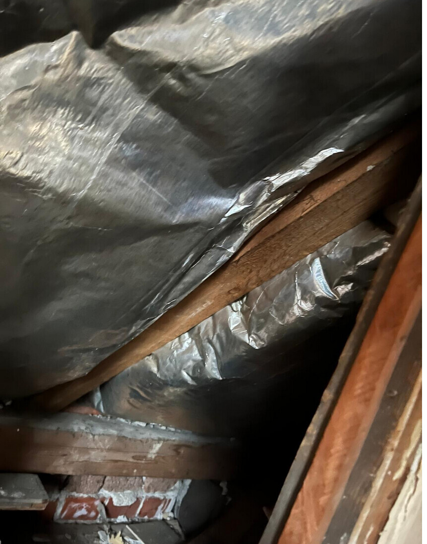 Dachboden mit Dämmung: Aluminiumfolie-Isolierung und Holzbalken im Dachraum