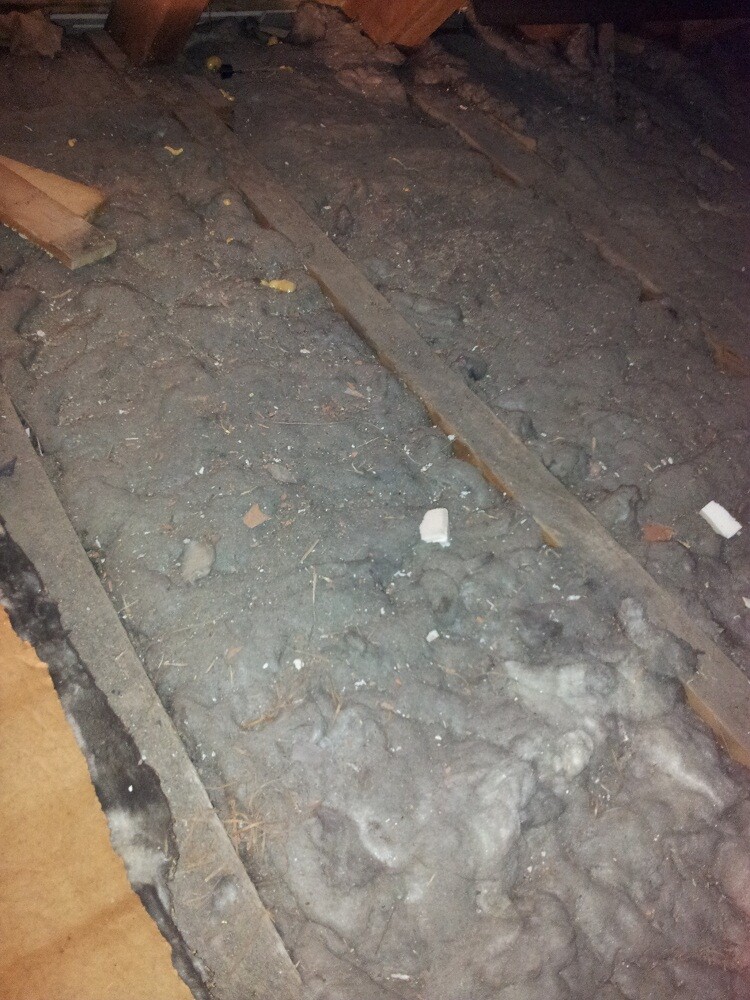 Dachboden mit Dämmmaterial, Holzbalken und losem Schutt am Boden