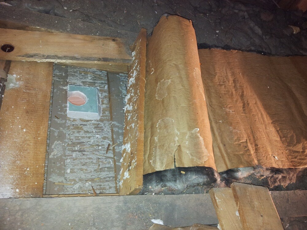 Dachboden mit Holzbalken, Dämmung und beschädigter Hülle sichtbar