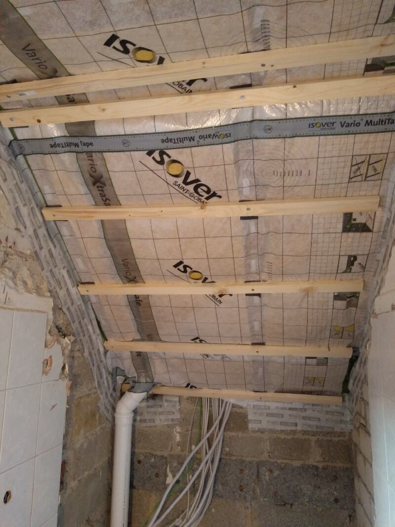 Decke im Bau mit Holzlatten, Isover-Dämmung, PVC-Rohr und Kabelstränge an der Wand.