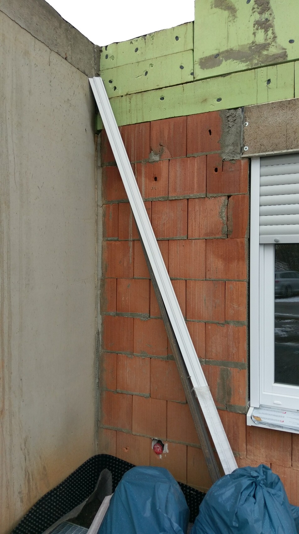 Außenwandbau mit Ziegel, grüne Dämmplatten und Fenster auf Baustelle
