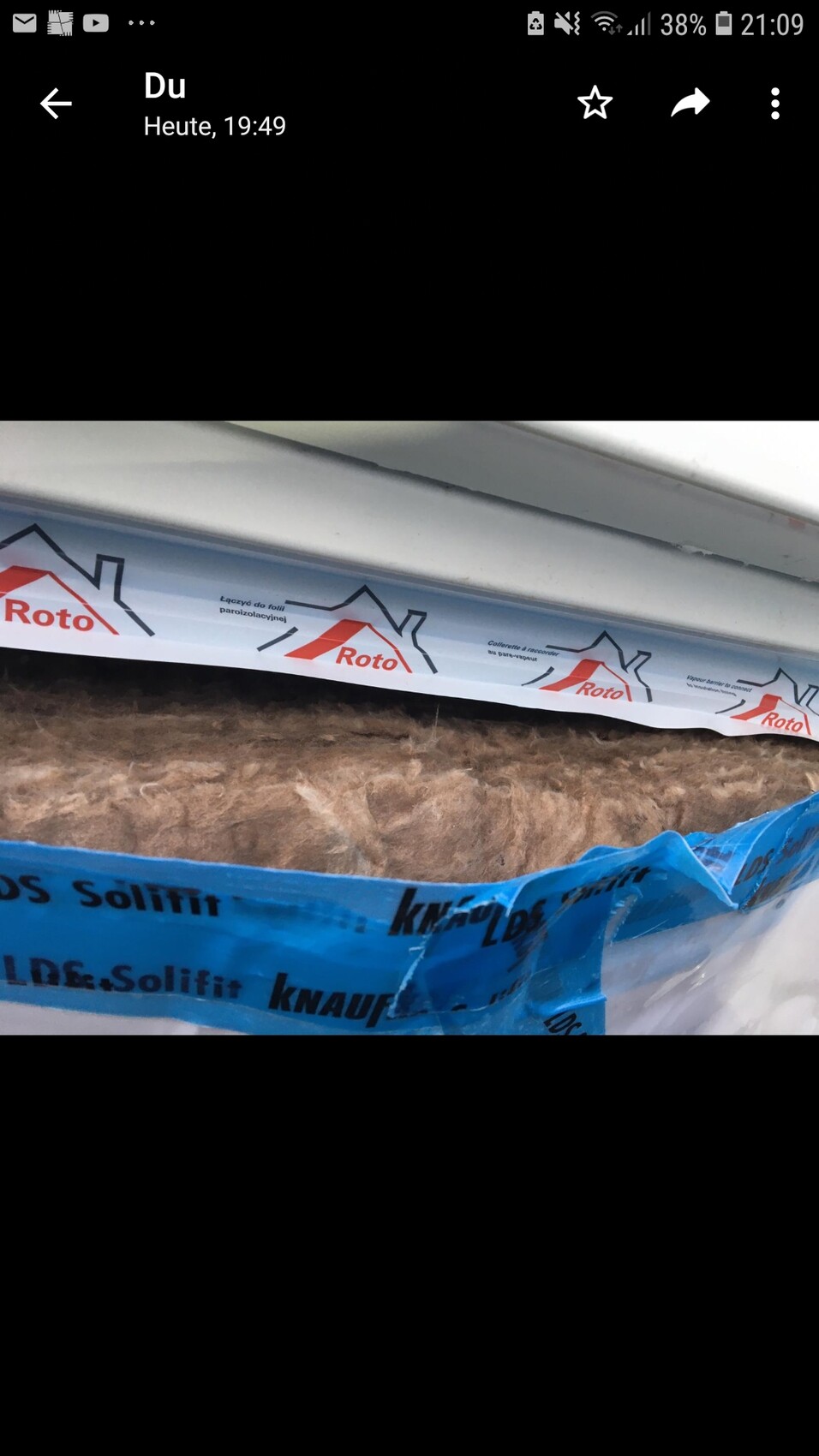 Dämmmaterial an Gebäudehülle mit blauem Knauf-Band und Roto-Logo