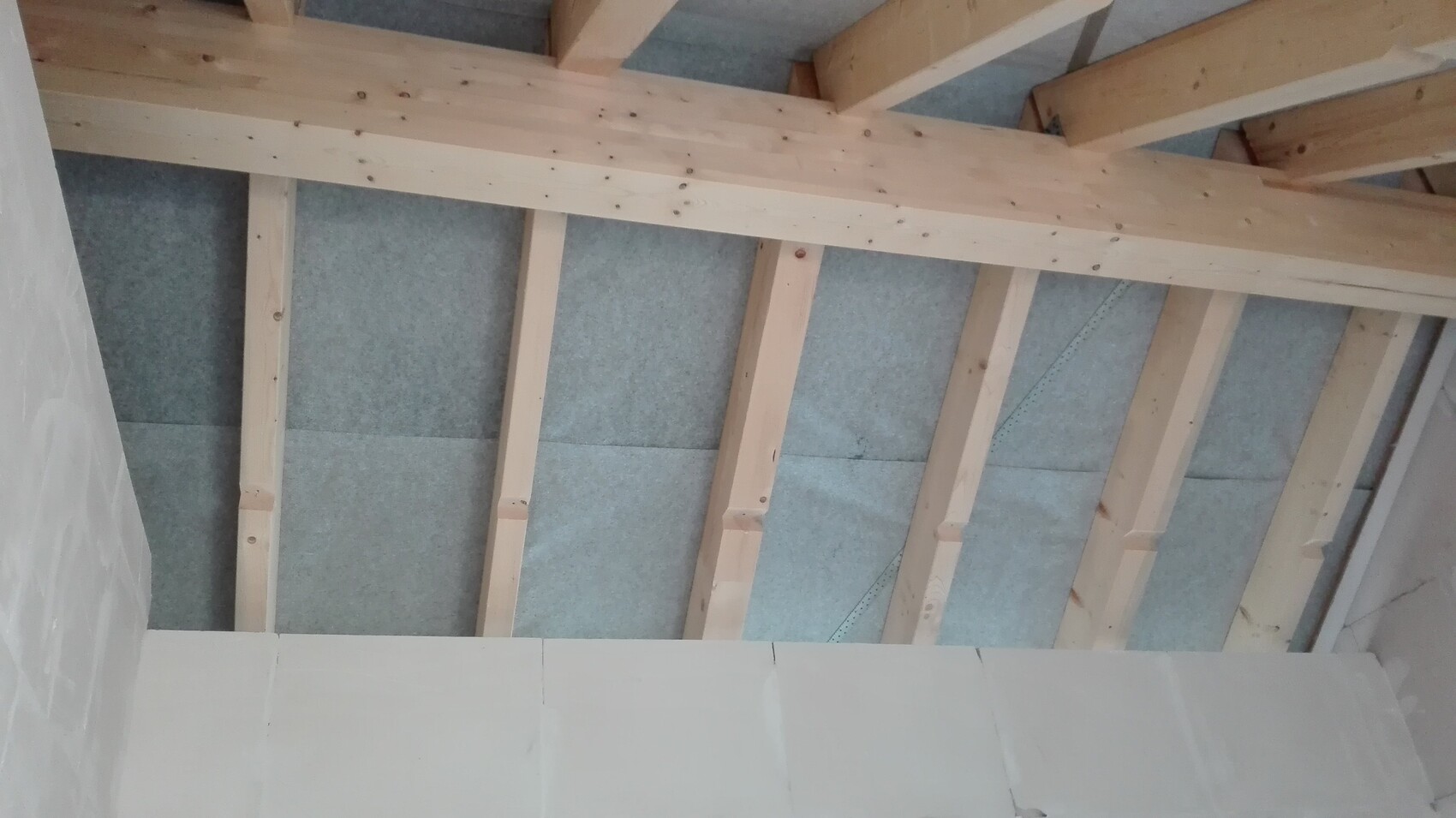 Holz-Dachstuhl mit Dämmplatten zwischen Balken im Rohbau