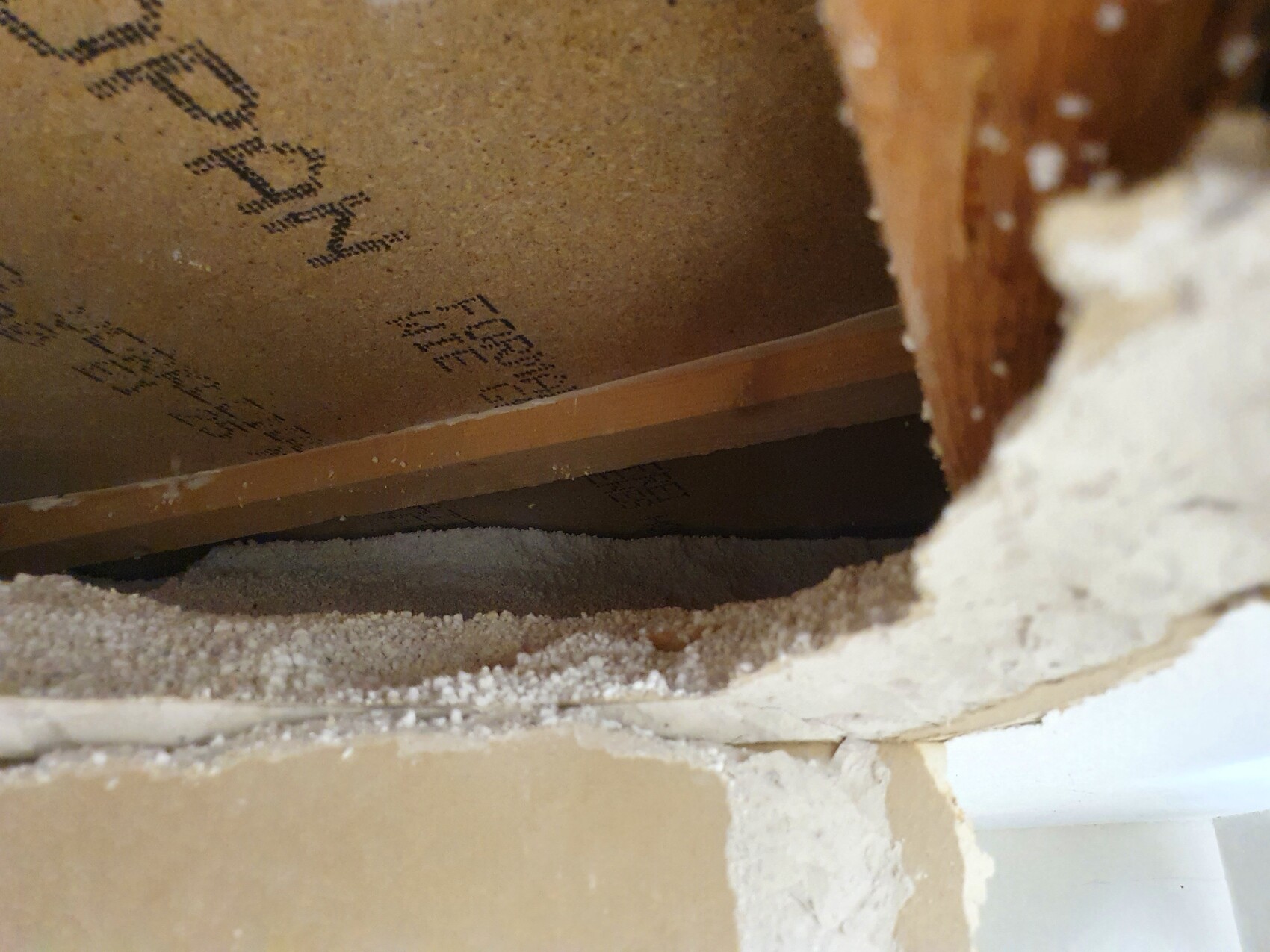 Offene Wandöffnung mit Holzrahmen, Staub und Putzresten im Raum.
