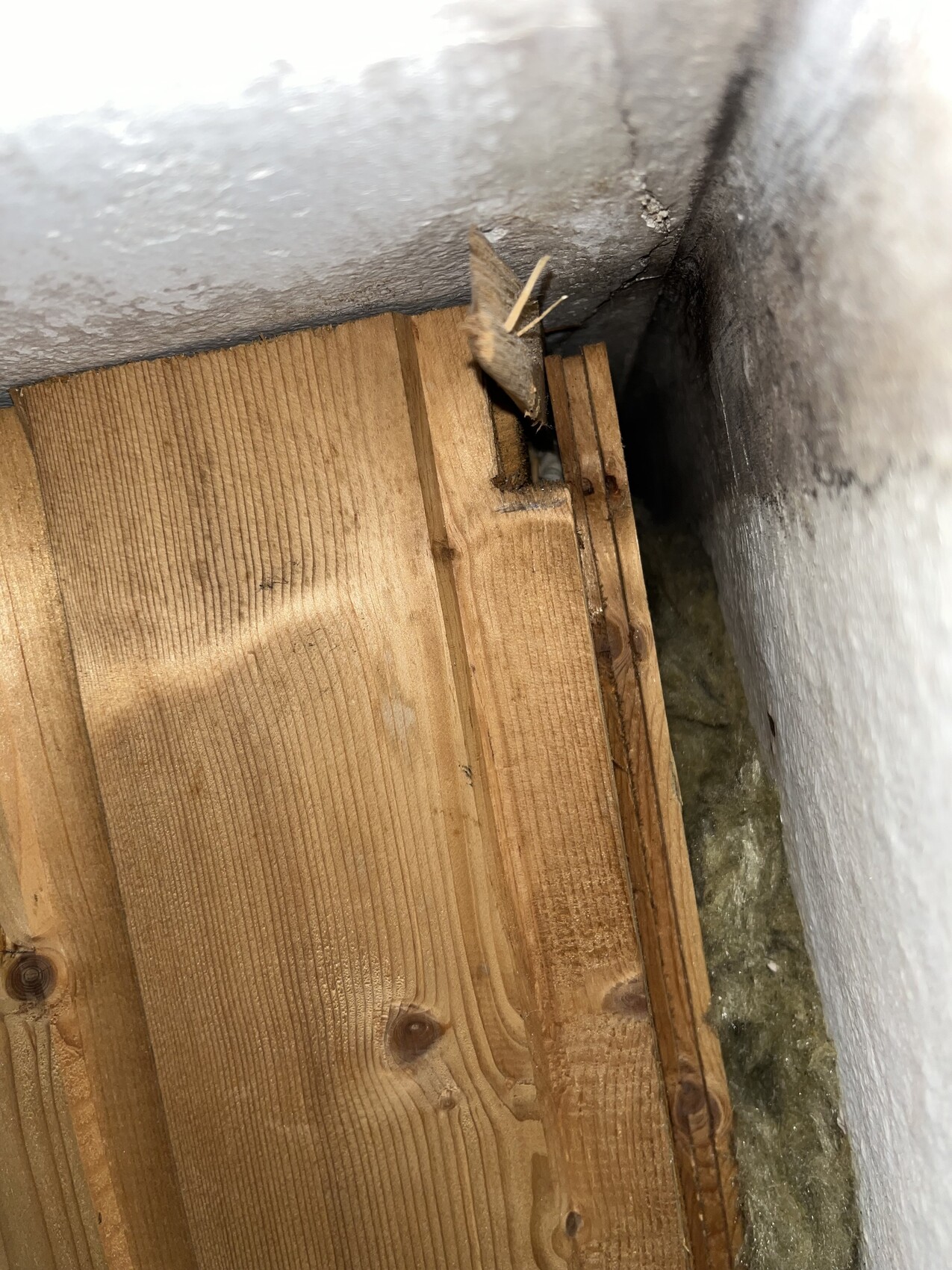 Holzlatten stapeln sich in einer Wandöffnung neben Dämmmaterial in der Ecke