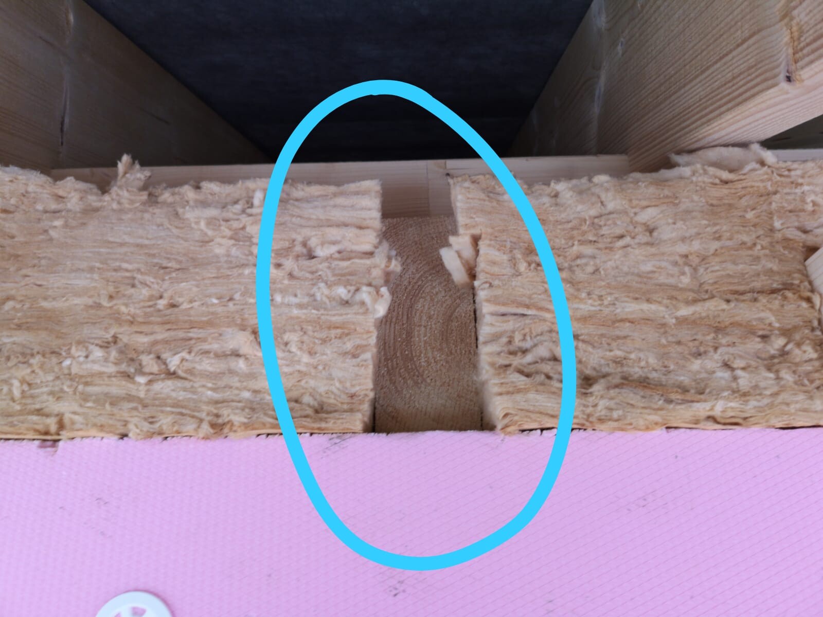 Baustellenszene mit Dämmung zwischen Holzbalken in der Wand